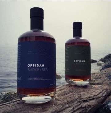 A shot of two bottles of&nbsp; Oppidan Smoke + Sea Bourbon on the shoreline.
