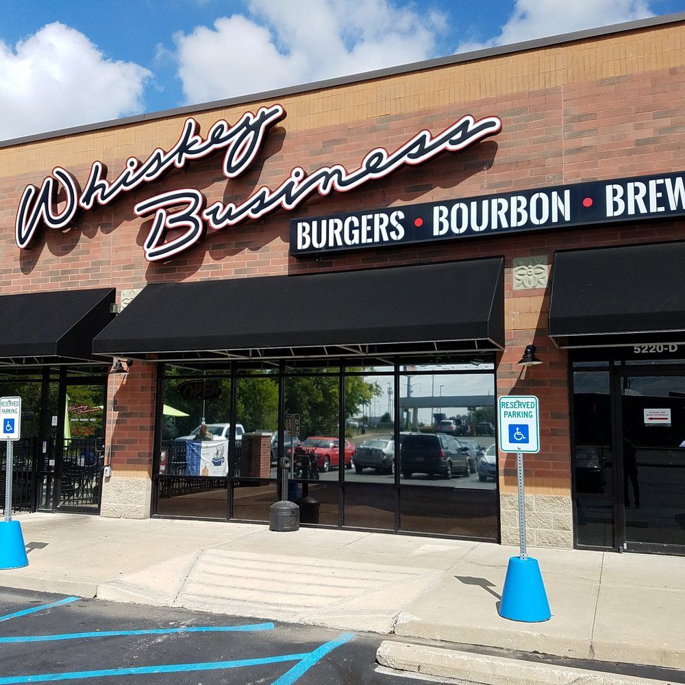 Whiskey Business’ facade with reserved parking signs with the name Whiskey Business in front of the building