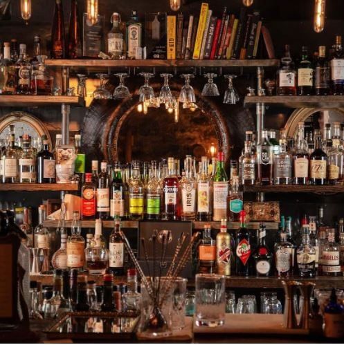 An image of Swordfish Tom’s bar with the shelves filled with bottles. Wine glasses hung upside down above the counter.