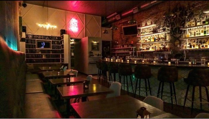 &nbsp;An image of SoT’s bar. It is dimly lit with the bar lit up and surrounded by empty chairs and tables.